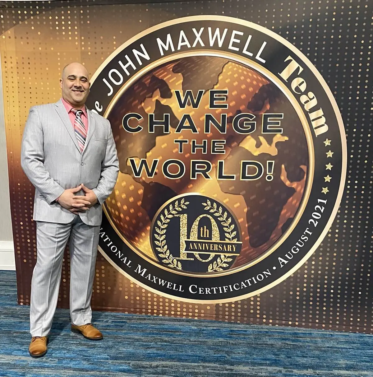 Man standing beside a large John Maxwell Team emblem.