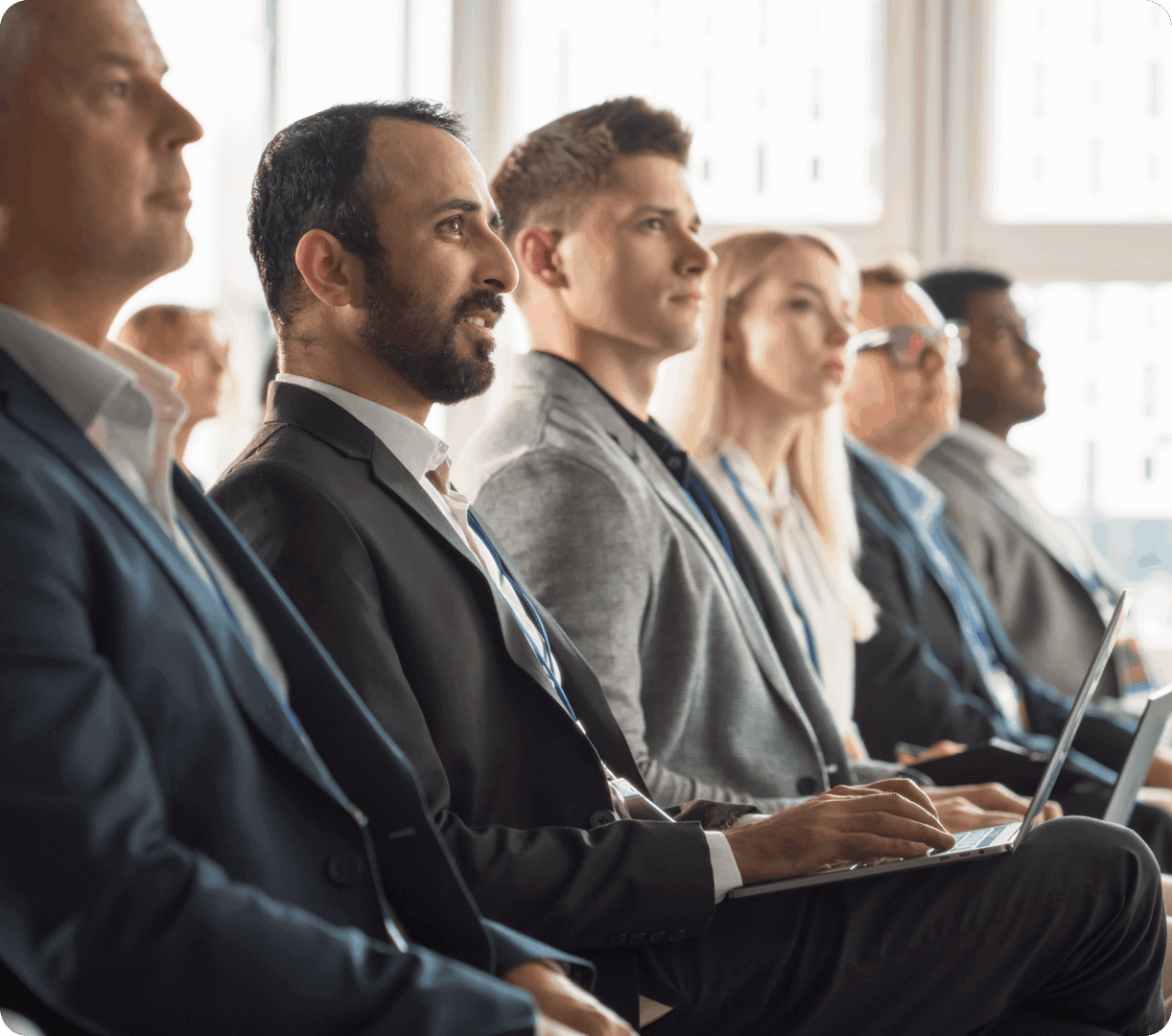 Diverse professionals attentively listening in a formal meeting or seminar.