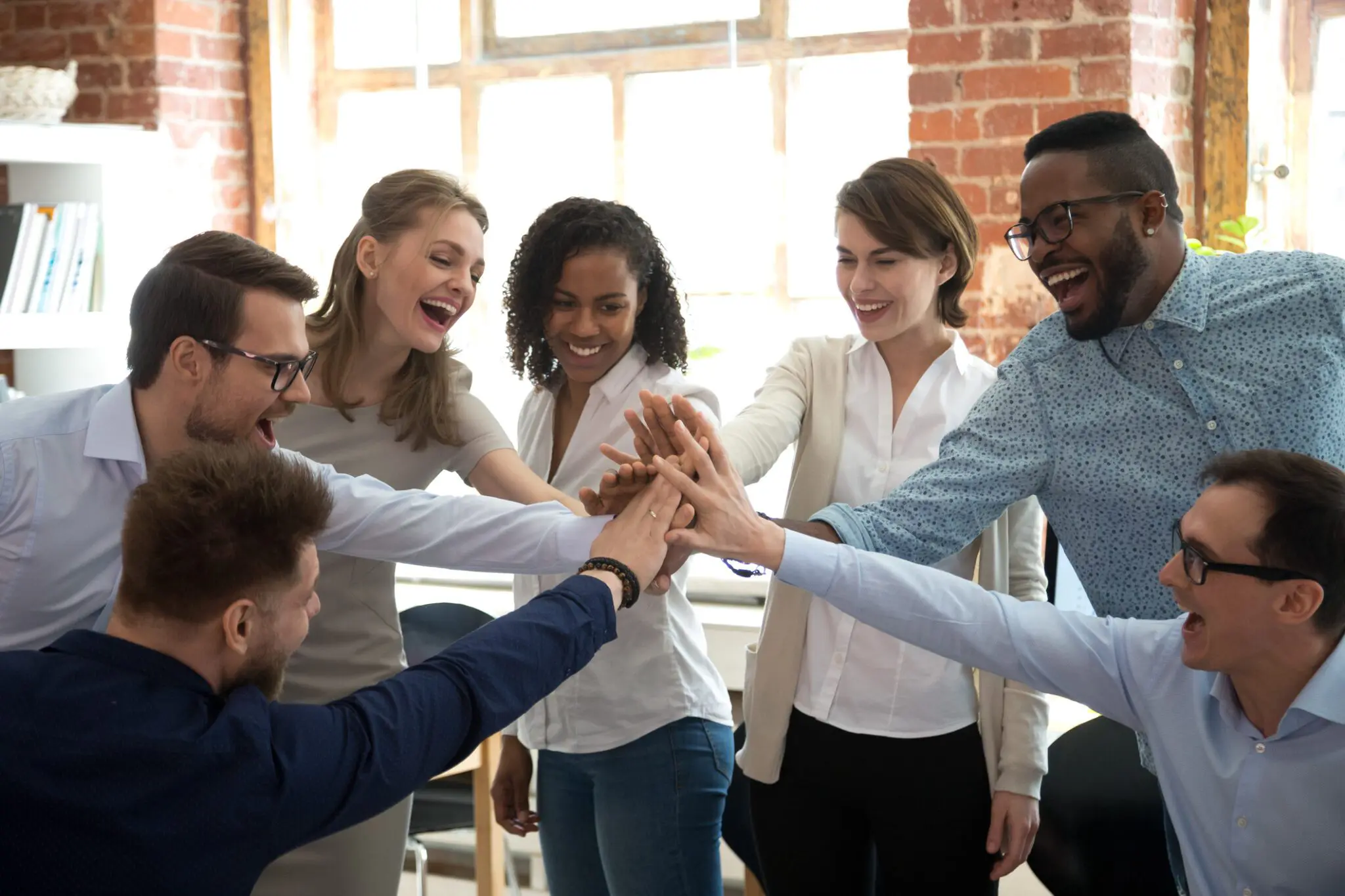 A group of diverse coworkers joining hands in teamwork.