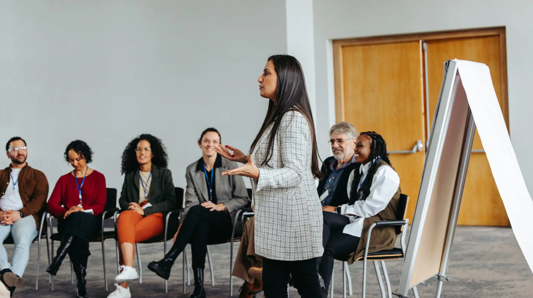 A woman presenting to an attentive audience in a professional setting.
