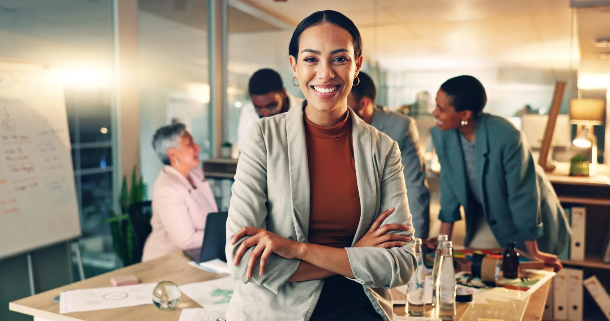 Confident businesswoman smiling in a busy office.