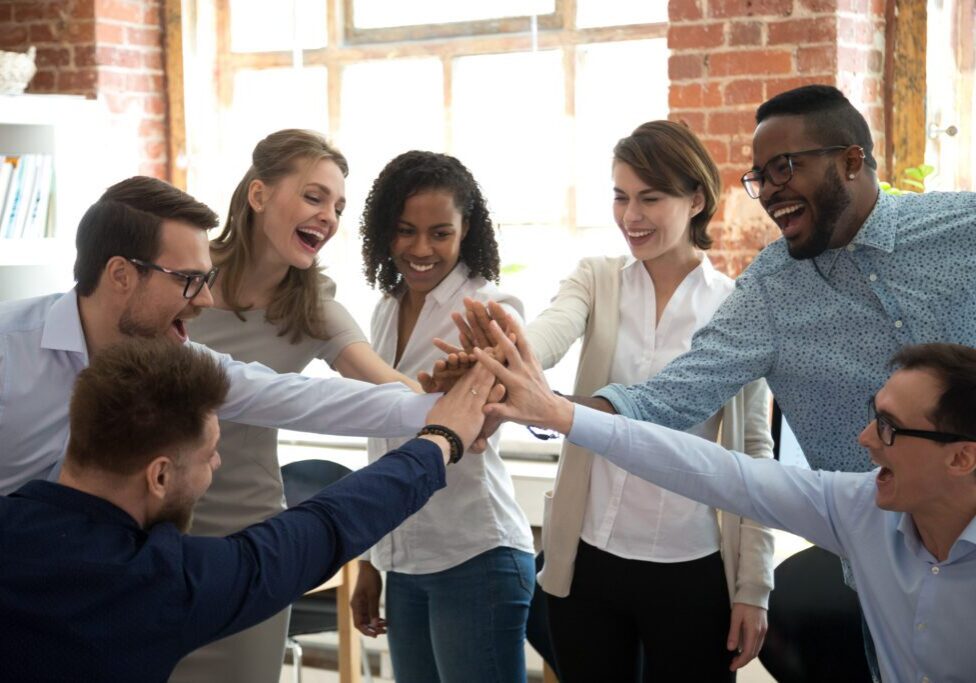 A group of diverse coworkers joining hands in teamwork.