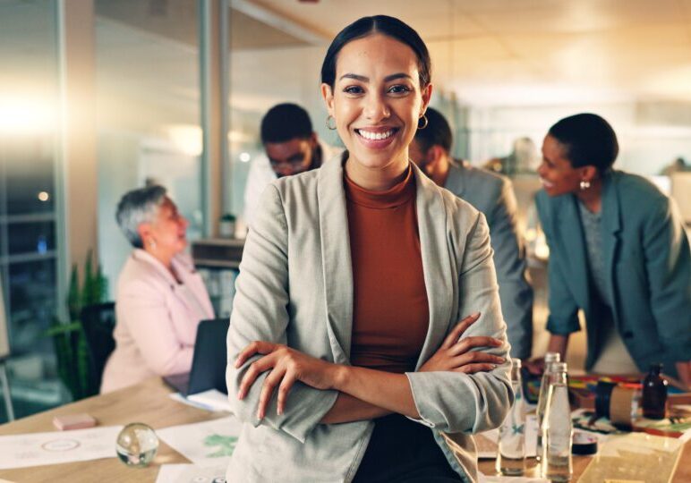 Confident businesswoman smiling in a busy office.